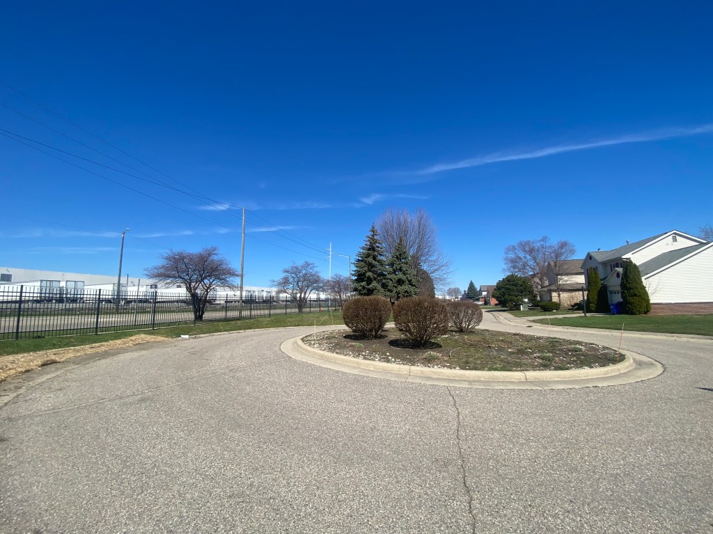 Image of warehouse with large trucks across the street from residential houses.