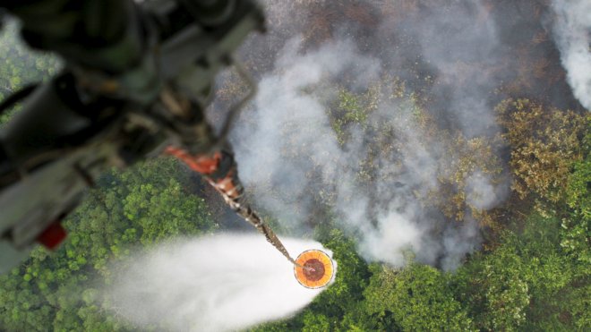 A helicopter drops water to extinguish a fire at a plantation in Kubu Raya district, Indonesia