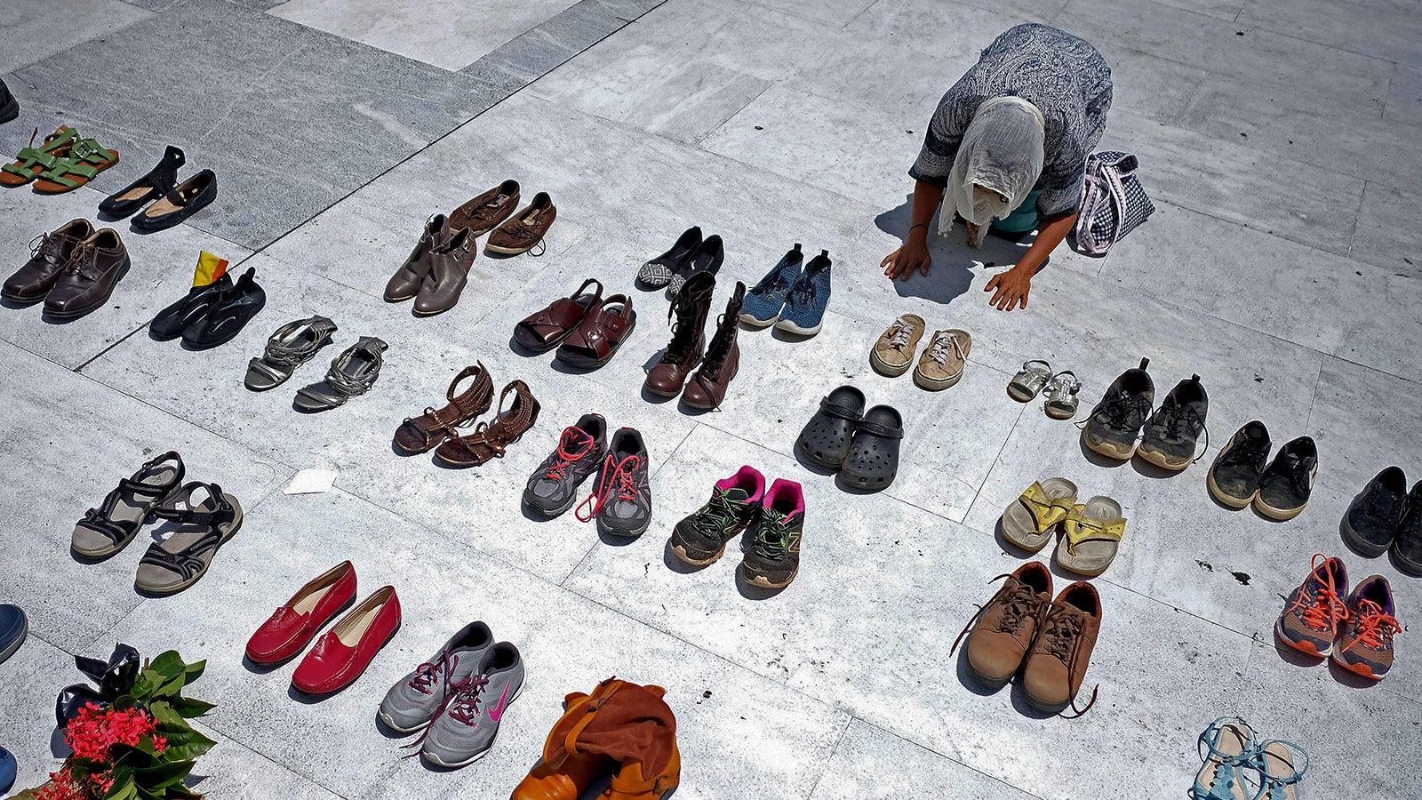 A woman prays in front of hundreds of shoes that were displayed in memory of those killed by Hurricane Maria in front of the Puerto Rican Capitol, in San Juan on June 1, 2018.