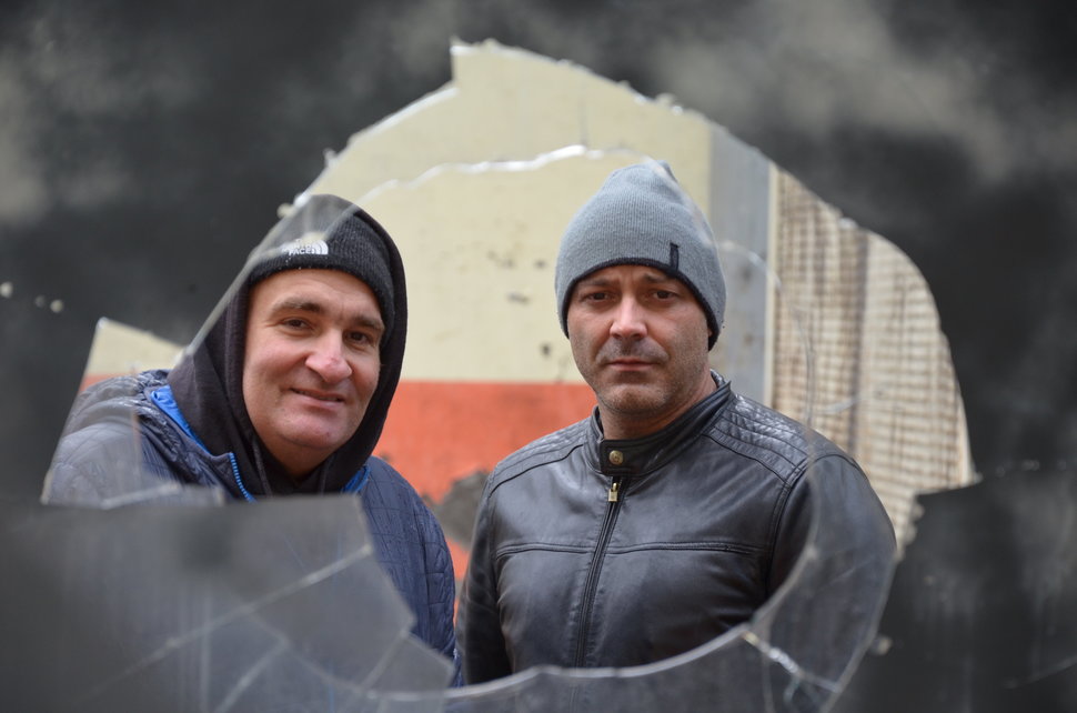 Miners Salvador Osario and Omar Garcia Alvarez look through a window in derelict mine.