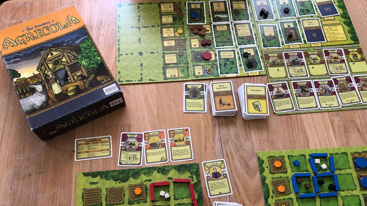 A photo of the game board for Agricola showing the box and playing cards.