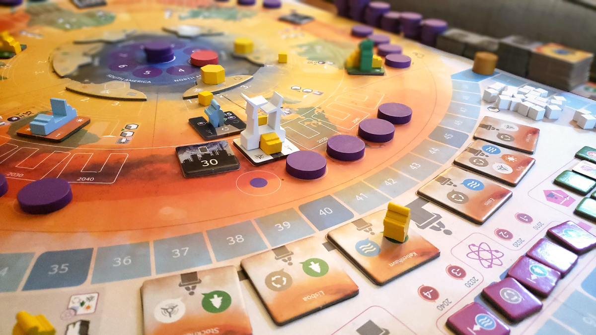 A photo of the game board for CO2: Second Chance. Various tokens and cards are scattered around a small wooden wind turbine.