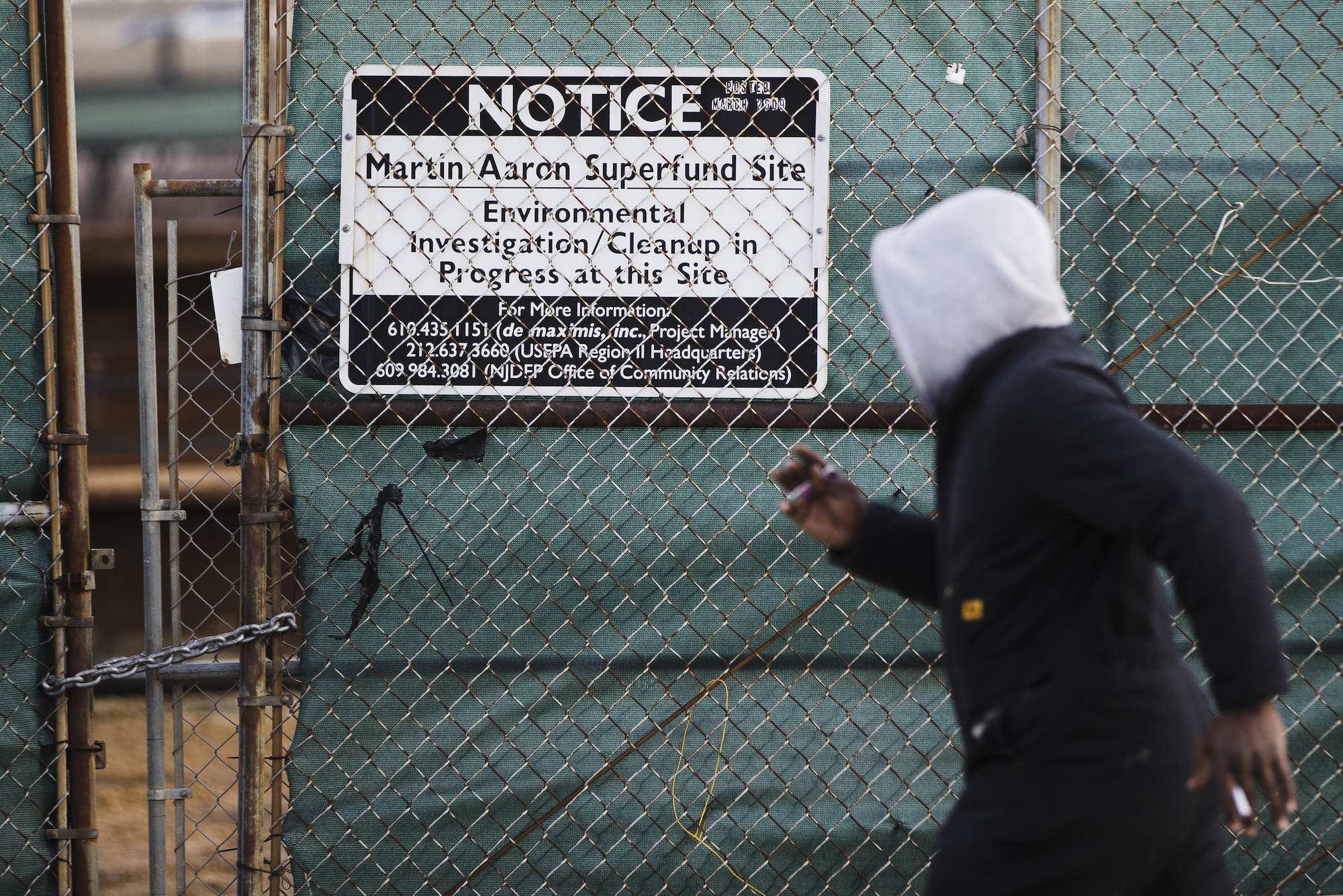 A photo of a man waking past a sign for the Martin Aaron Inc. Superfund site in Camden, New Jersey
