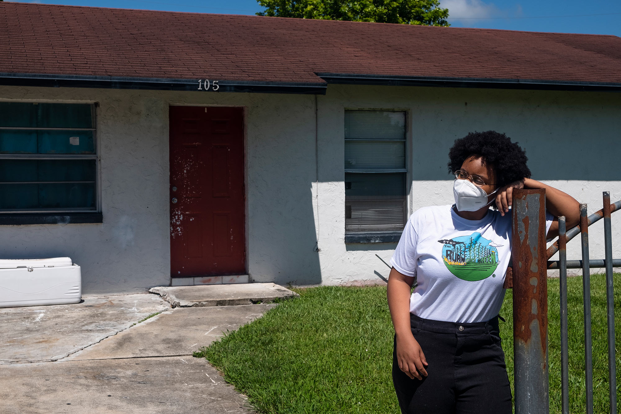 Kil’mari Phillips stands outside her home in South Bay, Florida — a few hundred feet away from Rosenwald Elementary School and the acres of sugarcane adjacent to it.