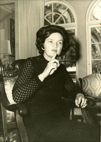 A sepia photo of a dark-haired woman sitting in a chair