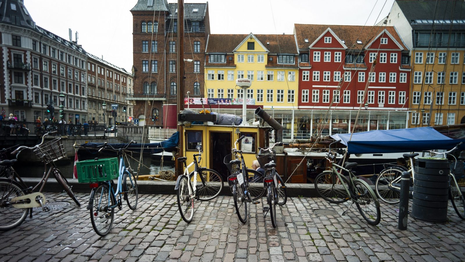 A photo shows a row of bicycles in front of a canal and colorful buildings.