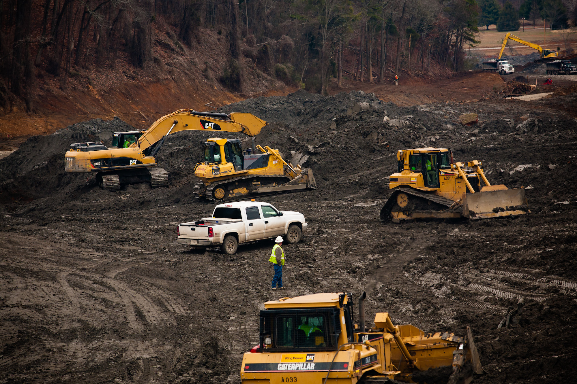 A photo of yellow bulldozers and workers in coal ash slurry