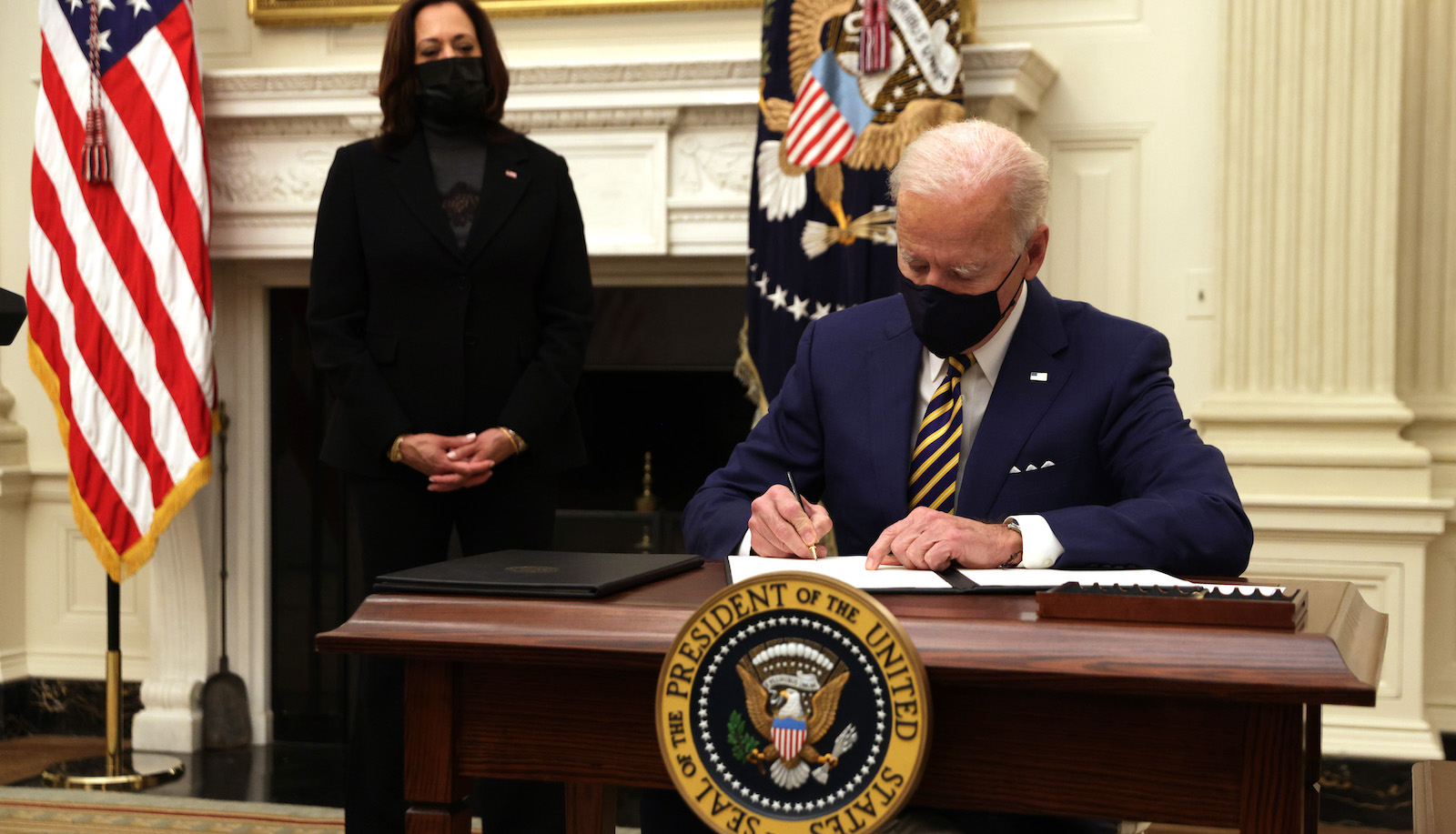 Biden signing executive orders behind his desk.