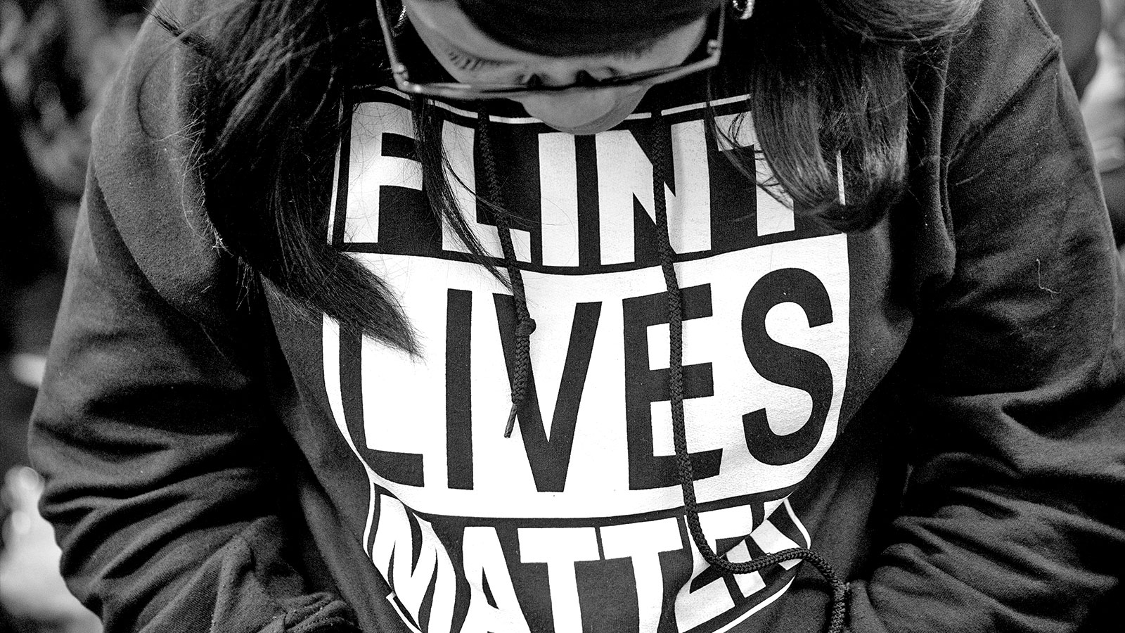 A close up photograph of a woman wearing a sweatshirt reading "Flint Lives Matter"