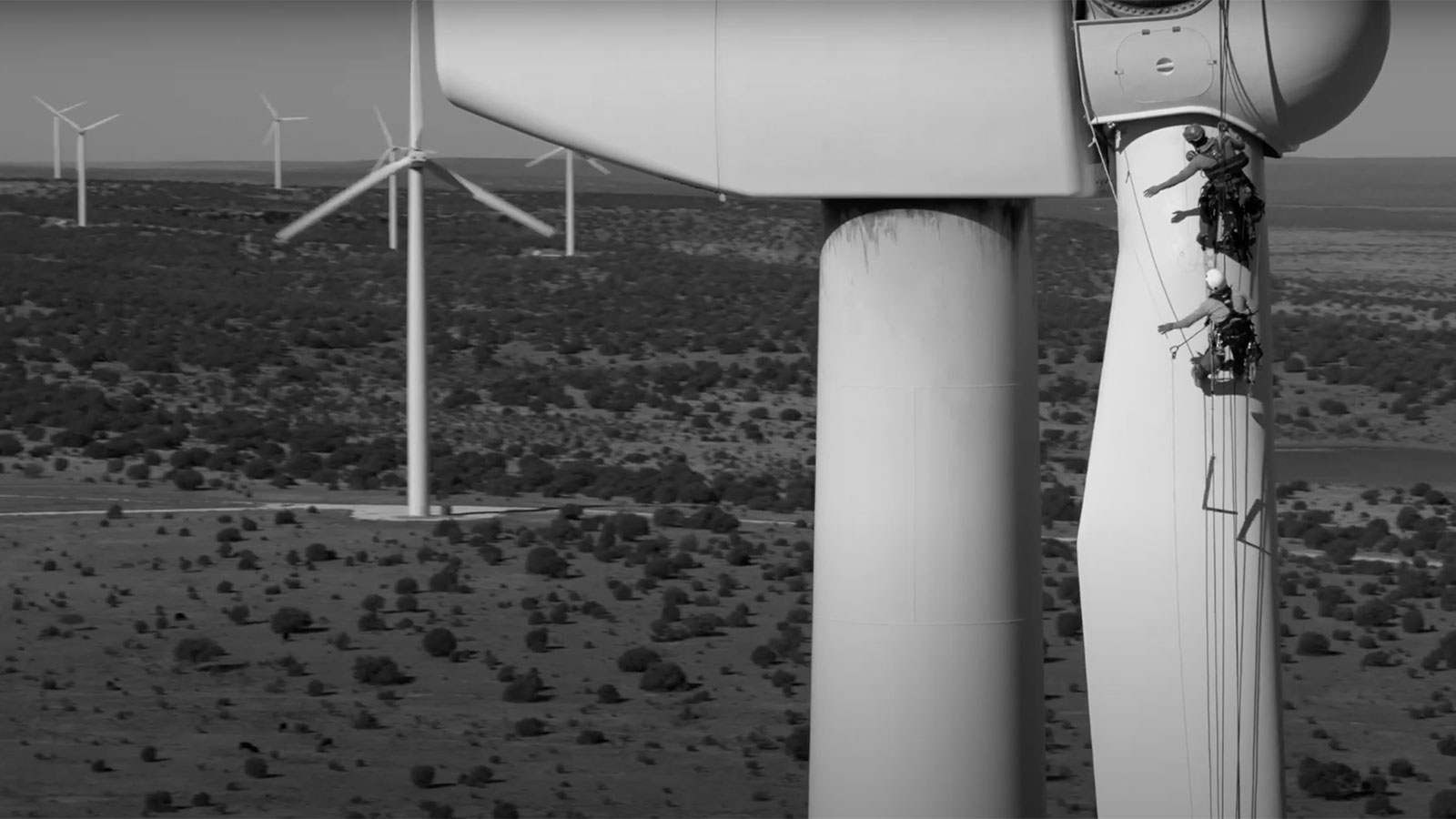 A screenshot from a video targeting builders for climate projects. Shows a landscape with wind turbines up close and in the distance