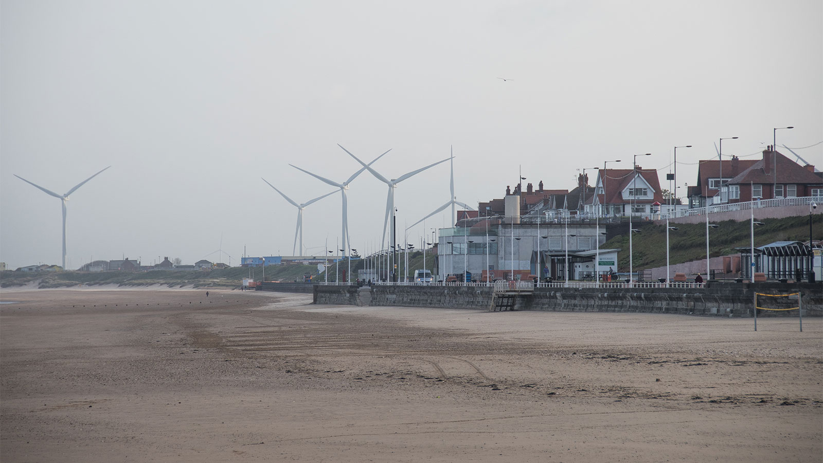 Photo of a beach community with wind turbines in the background
