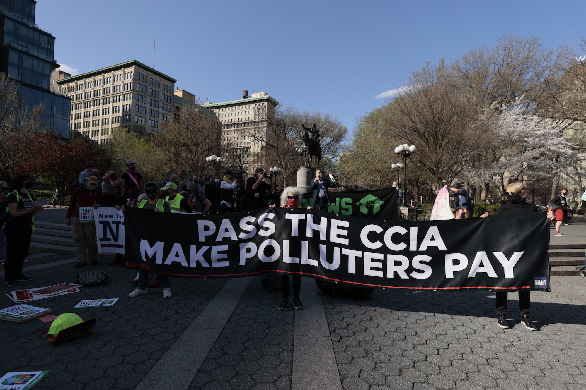a group of activists carry a large banner with white letters reading "PASS THE CCIA MAKE POLLUTERS PAY"