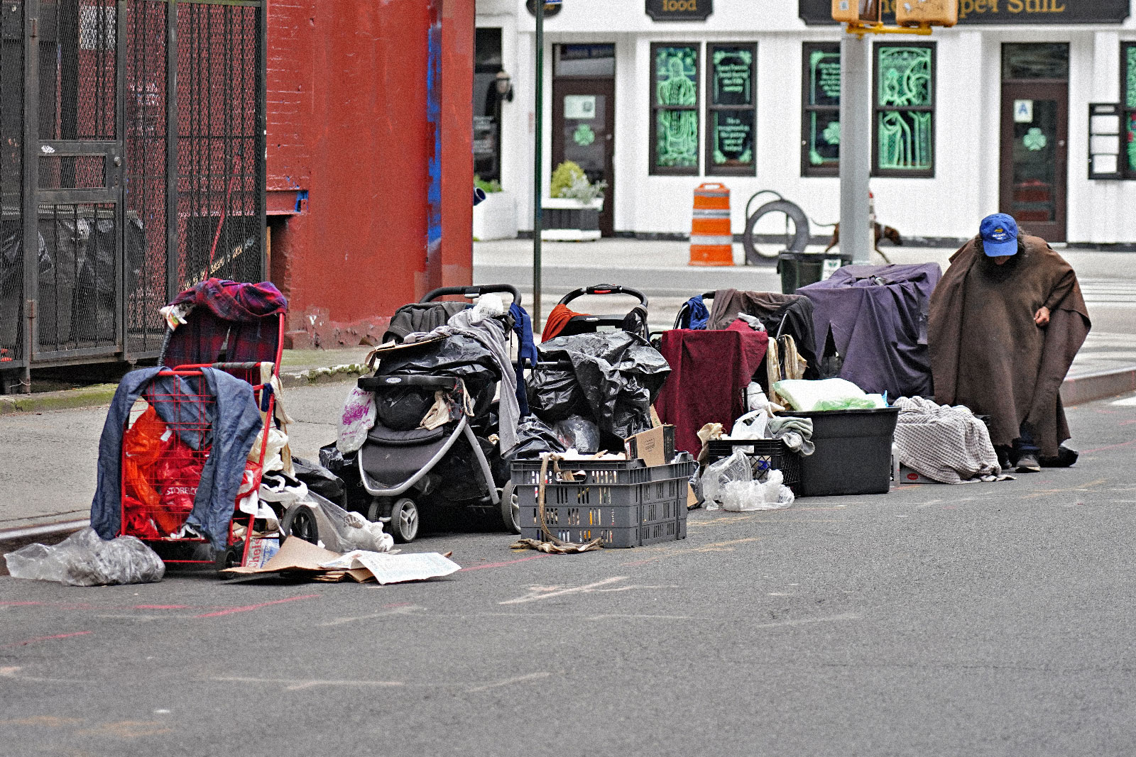 A homeless person sitting with their belongings on the street in New York City.