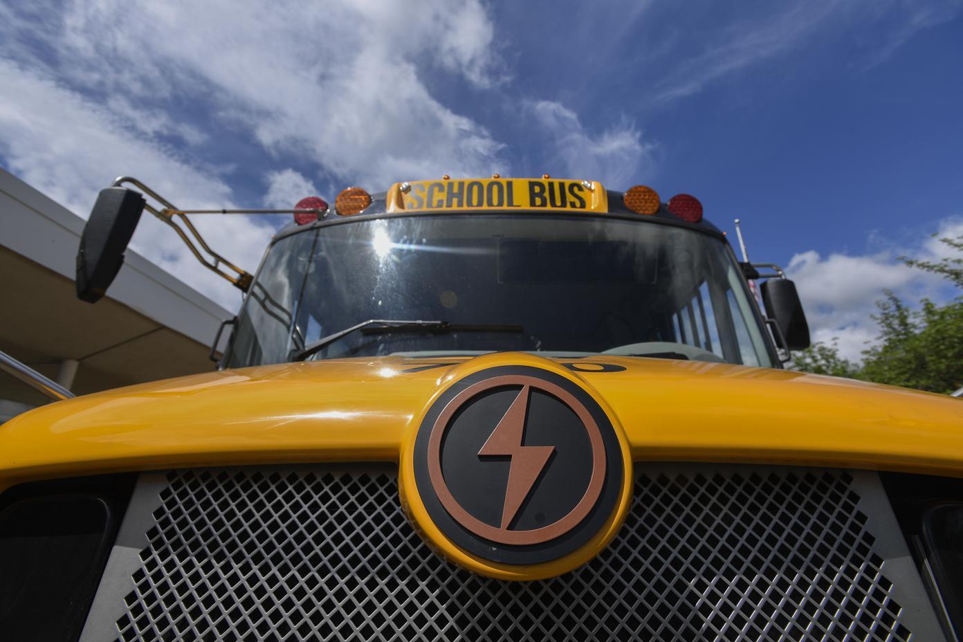 A close-up of the front of a yellow school bus with a big lightning bold logo on the front