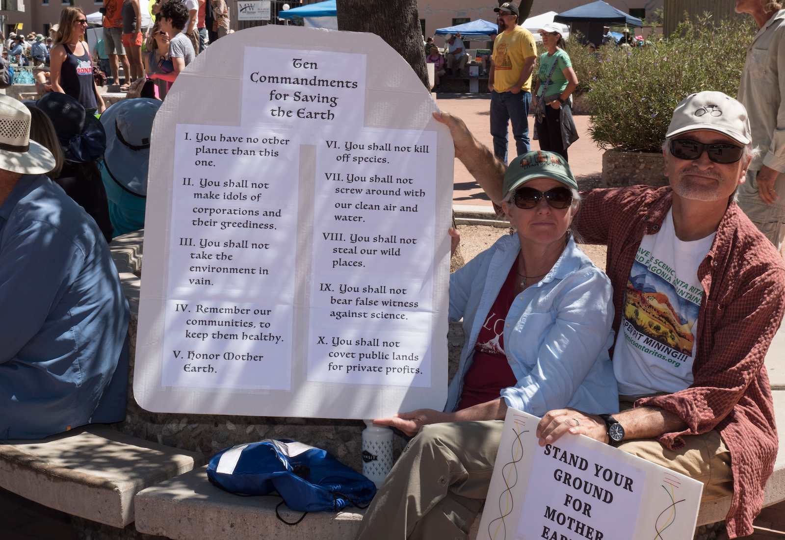 A couple holds up a poster with the "Ten Commandments for Saving the Earth" at the Arizona People's Climate March in 2017.