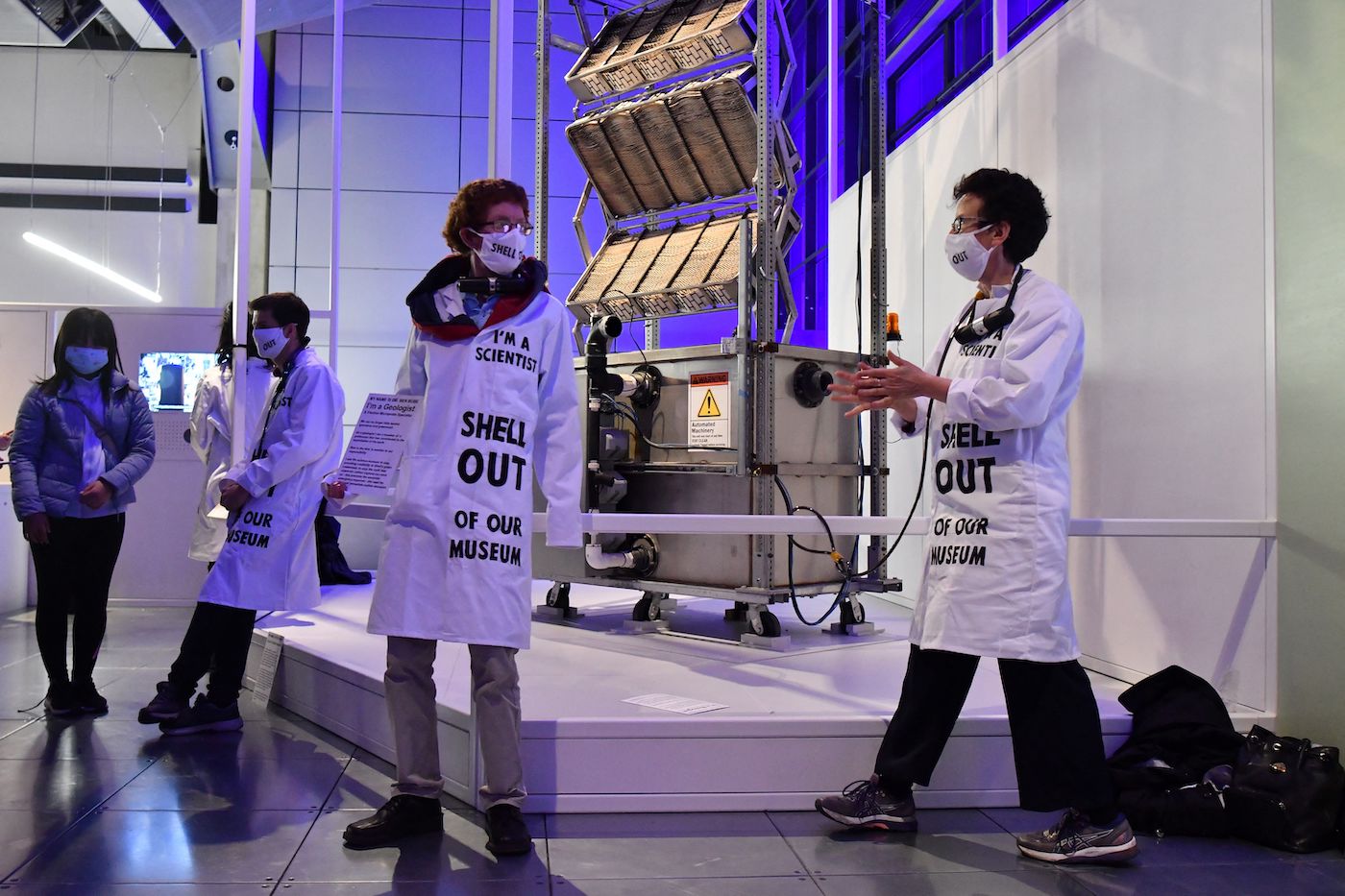Protestors chain themselves to a museum exhibit with coats that say I am a scientist, Shell out