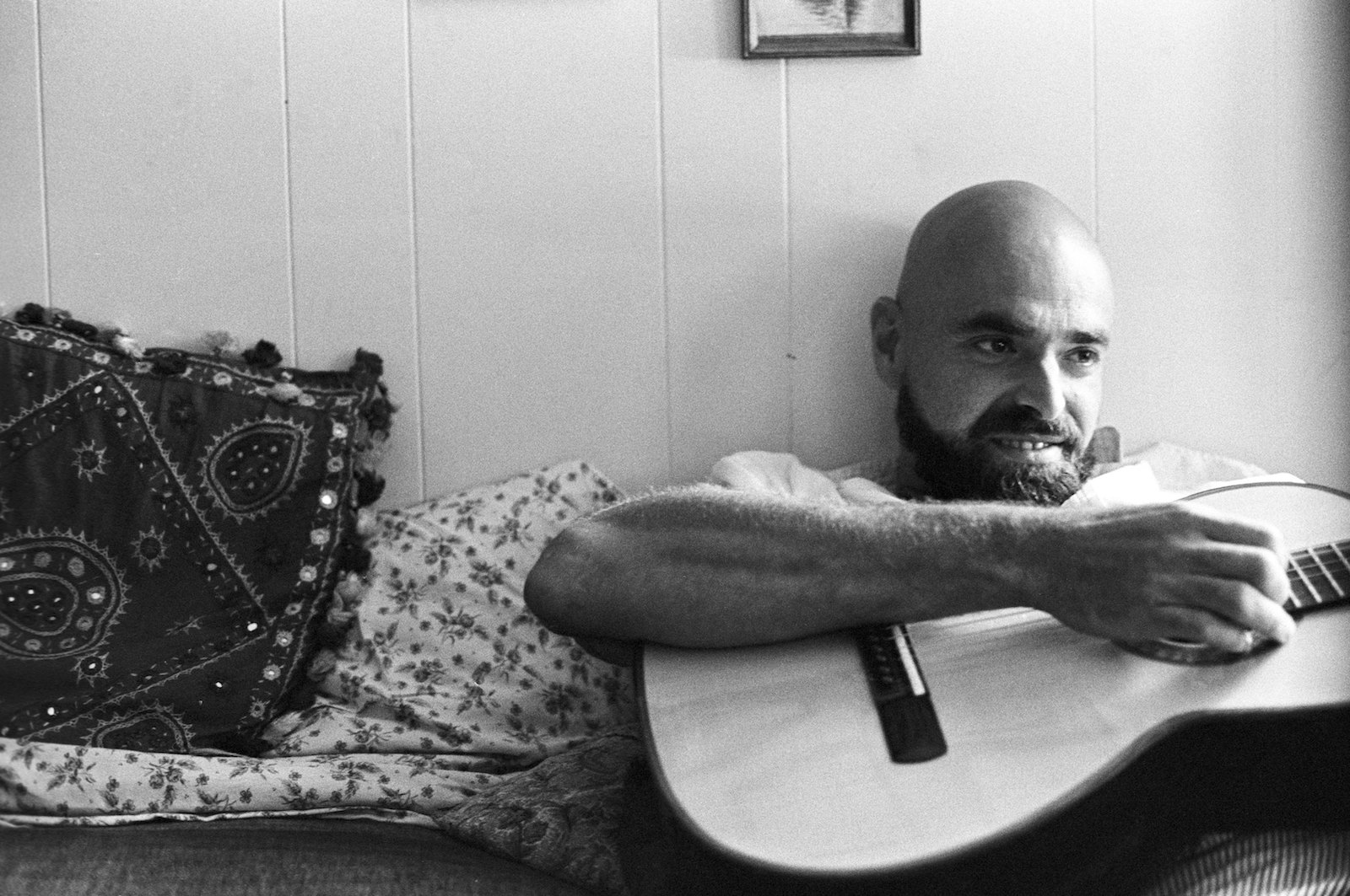 a black and white image of shel silverstein, who is a bald man with a beard holding a guitar