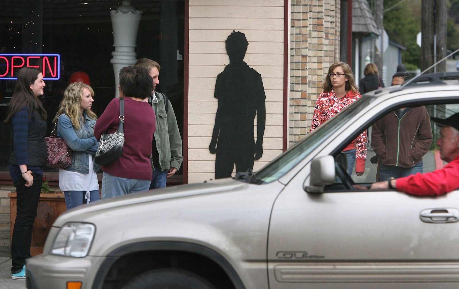 a cut-out of "Edward," the vampire protagonist from Twilight, pasted onto the side of a building while groups of normal people stand by