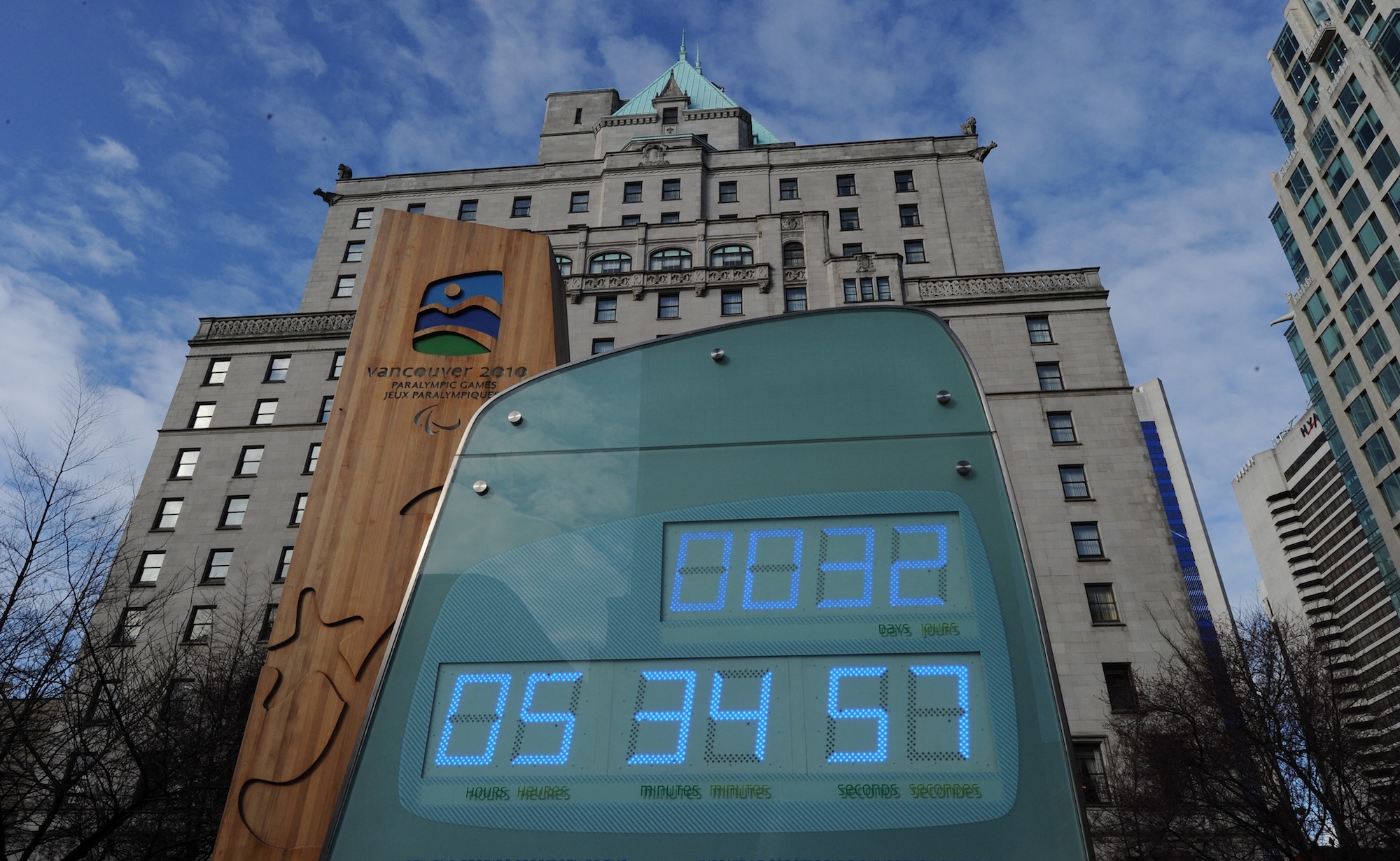 a large green sign with a countdown clock in days, hours, and minutes on a city street