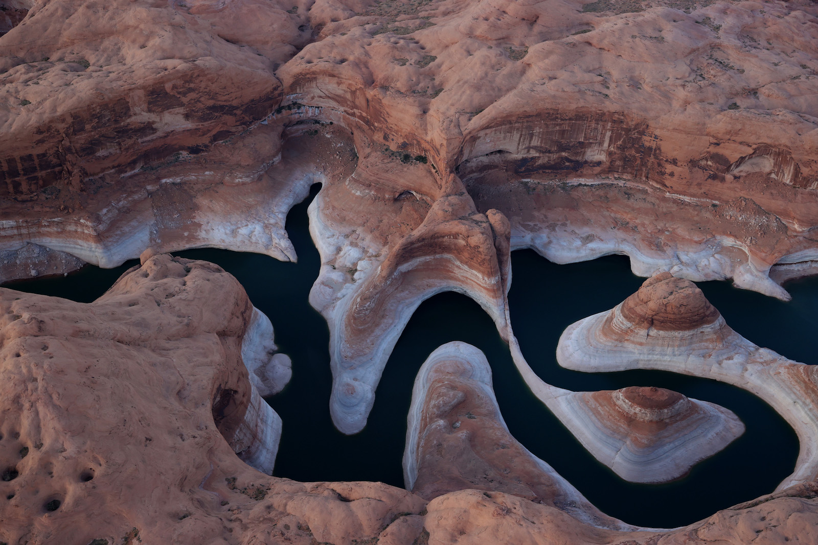 An aerial view of a very bendy portion of river with a ring of bleached rock marking water retreat due to drought