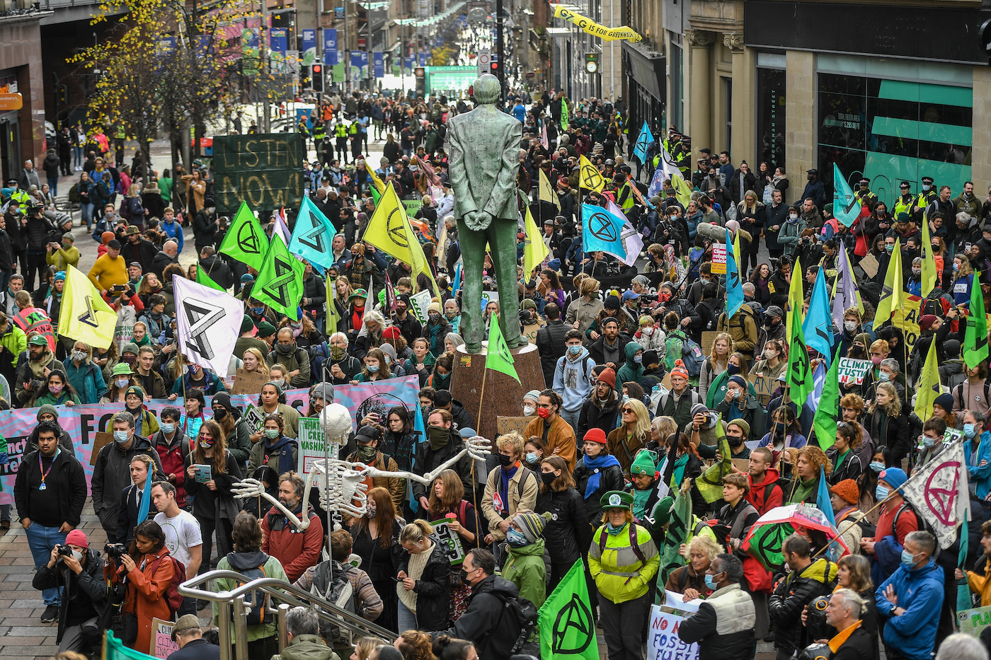 A large mass of protesters in the streets of Glasgow with extinction rebellion flags