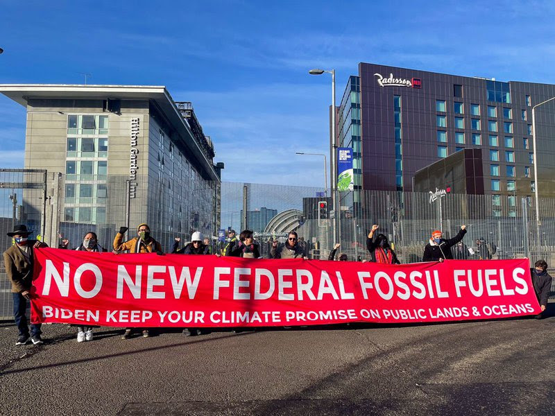 Protesters in Glasgow holding a banner that says no new federal fossil fuels