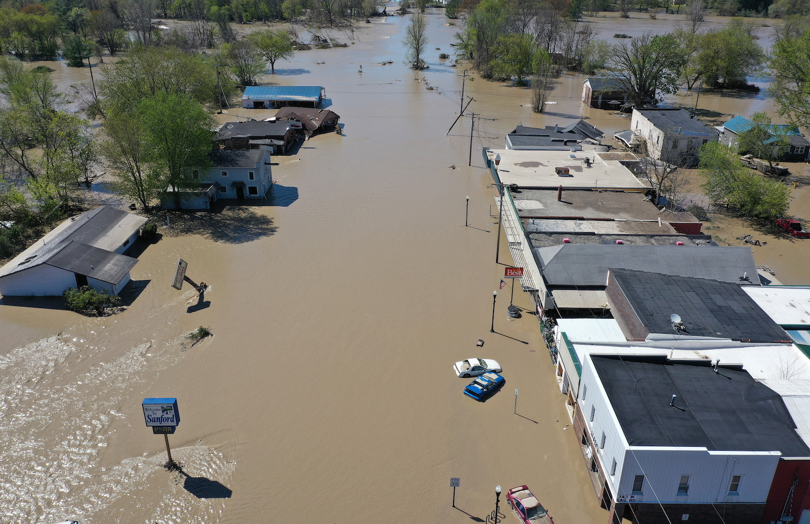 A streetview of a small town is submerged in brown water.
