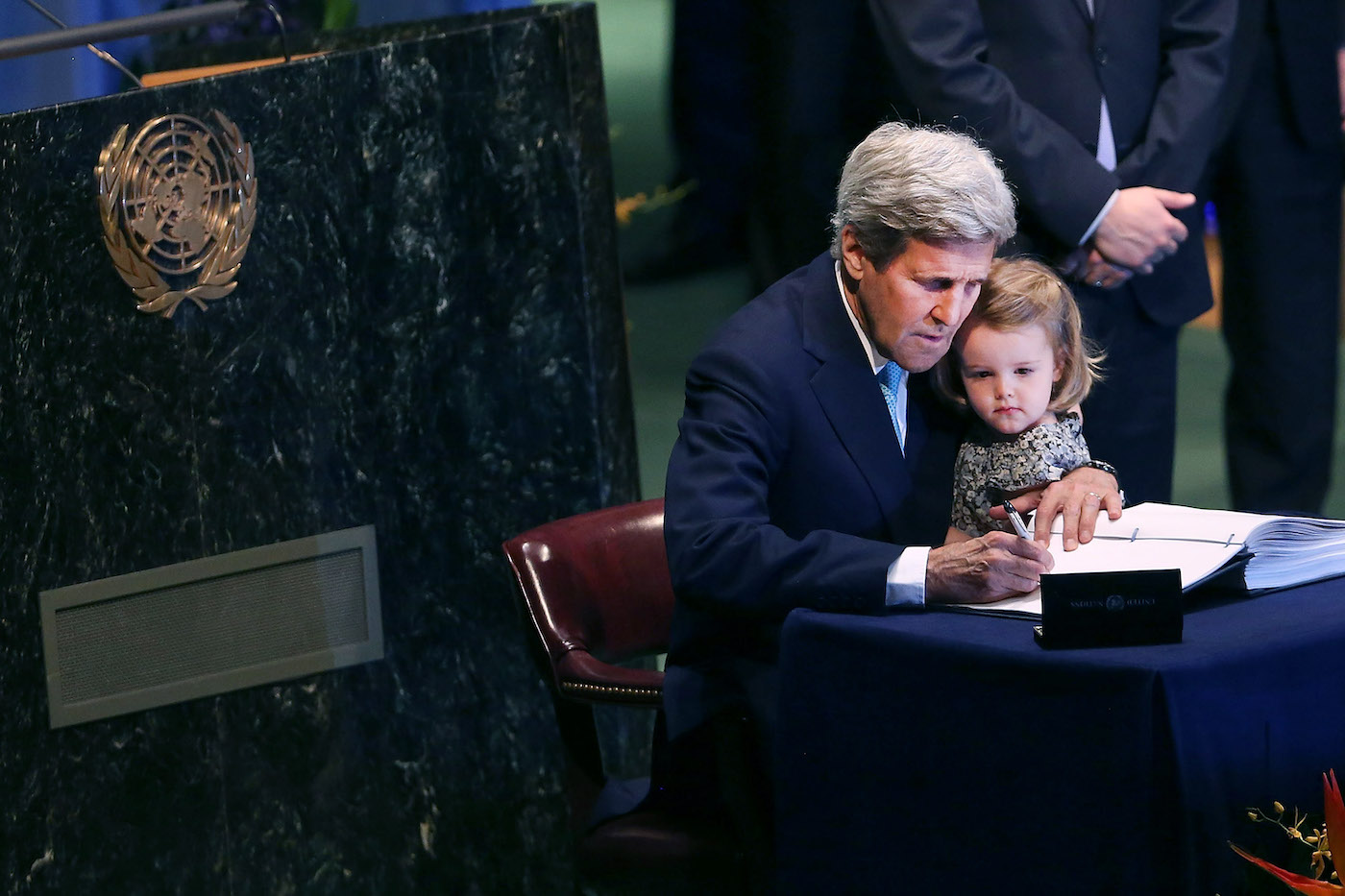 John Kerry signing the Paris Agreement in 2016 while holding his granddaughter