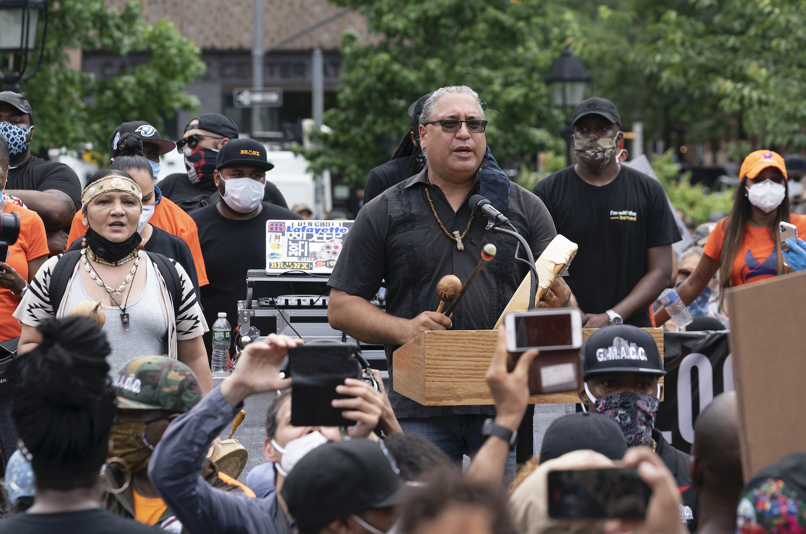 R. Mukaro Borrero speaks at a podium with a drum at a BLM protest