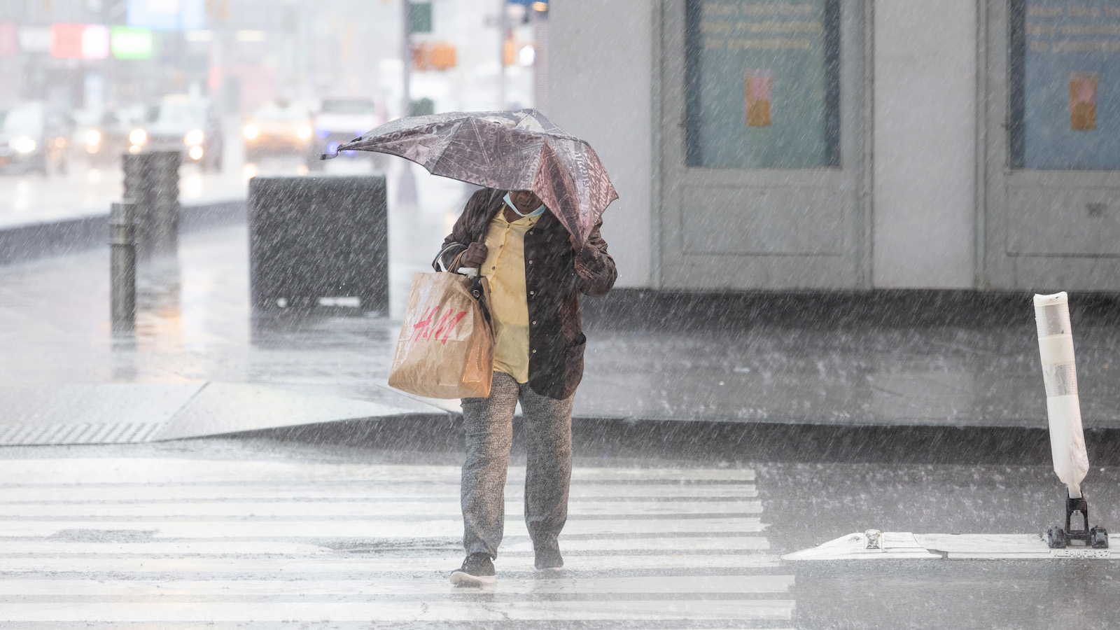 A woman with a broken umbrella walks through heavy rain