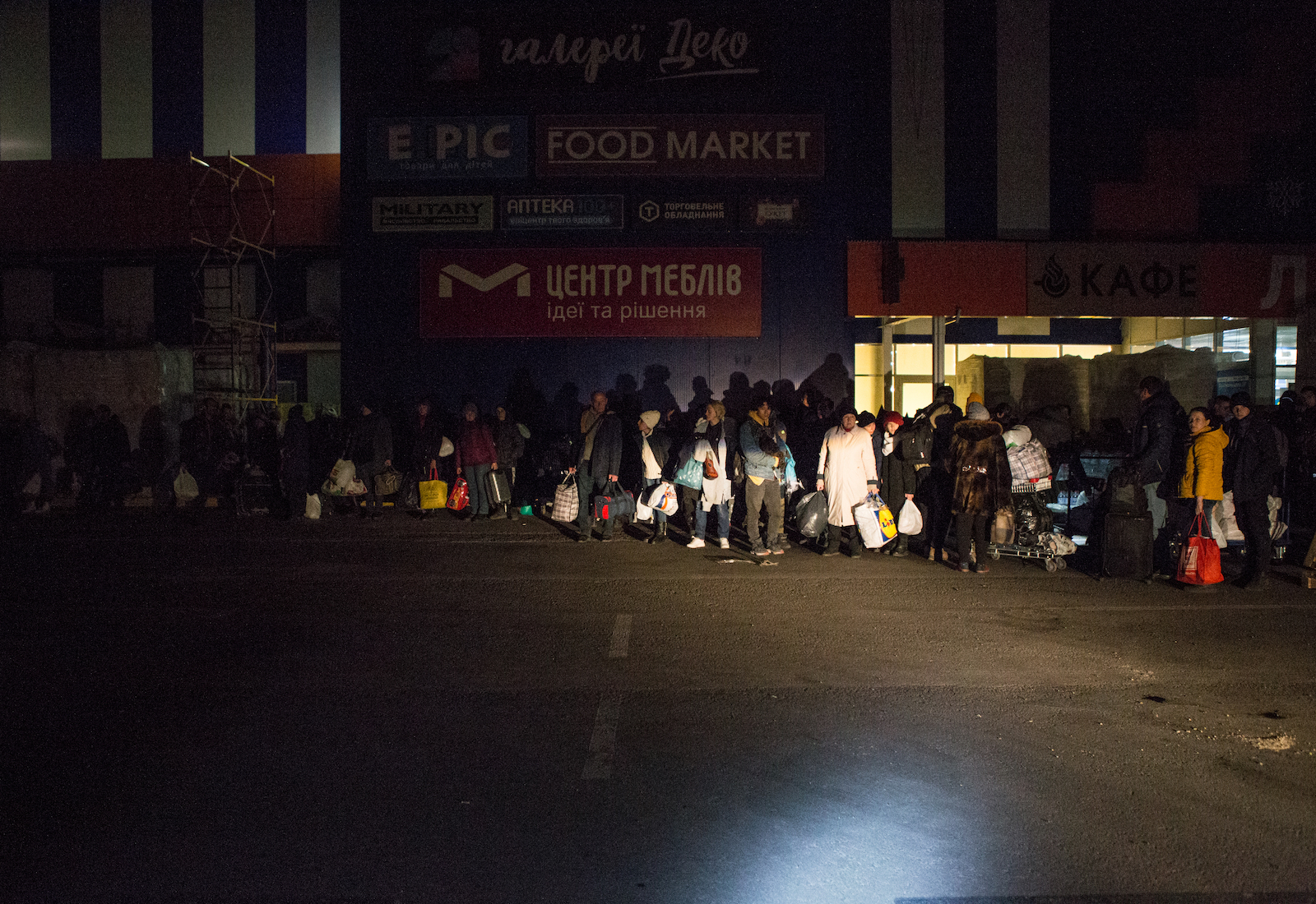 A line of Ukrainians huddle as they wait to evacuate on buses