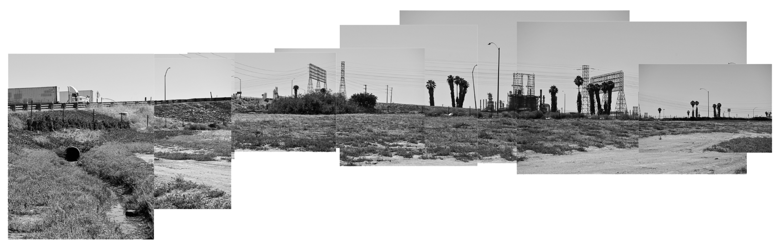 Black and white panoramic image made from multiple photos of land next to a highway with palm trees in the distance