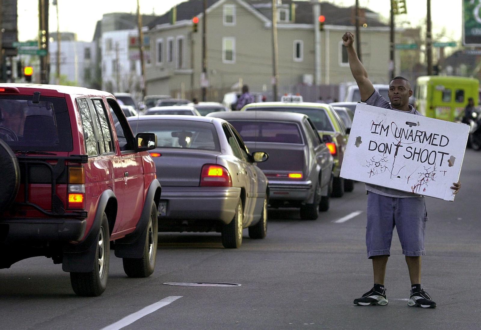 a man holds a sign near car traffic