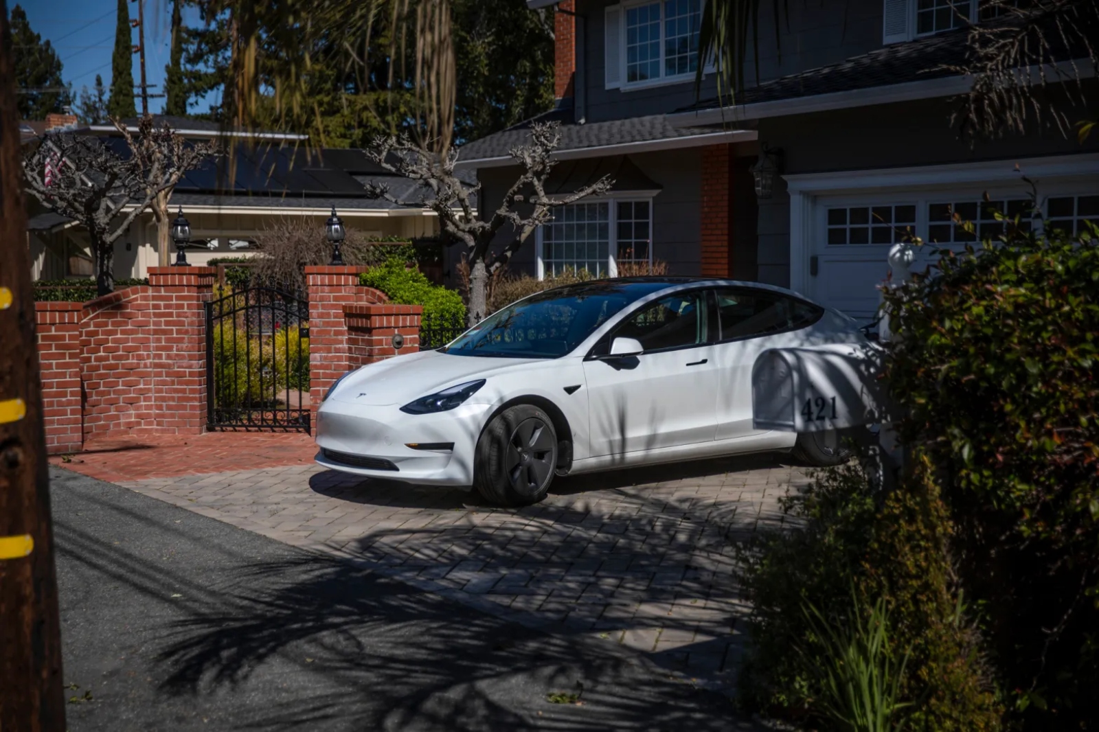 A white Tesla is parked outside of a home.
