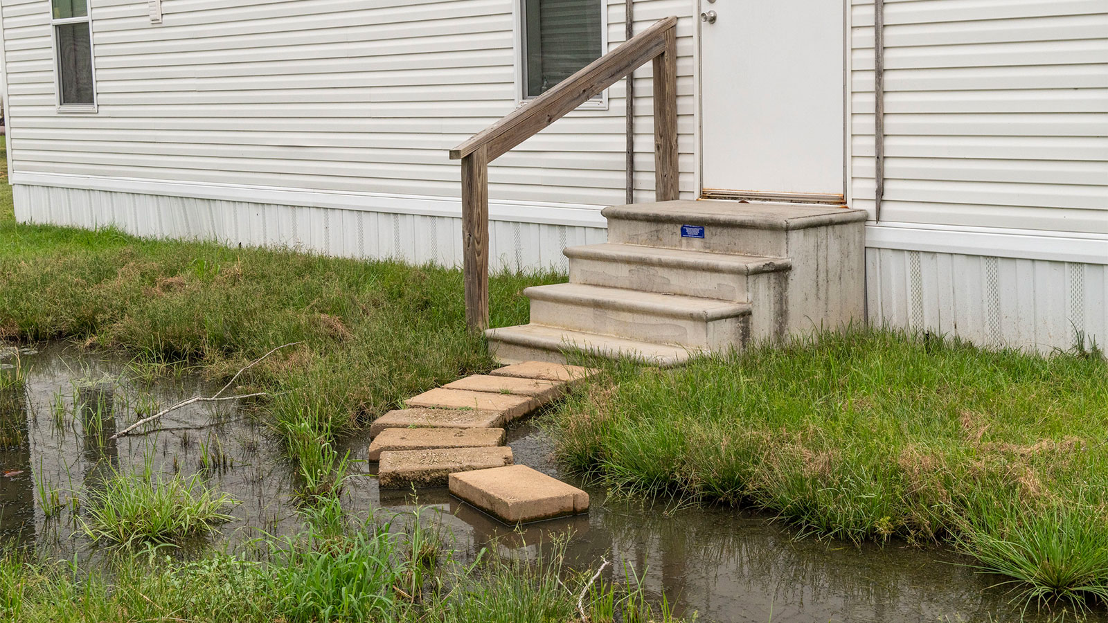 Steps leading to a home with sewage and wastewater in the yard directly below