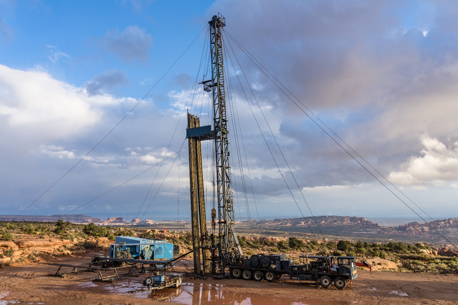 A pulling unit or workover rig on an oil well in Utah against the backdrop of the Monitor and Merrimac Buttes and Book Cliffs.