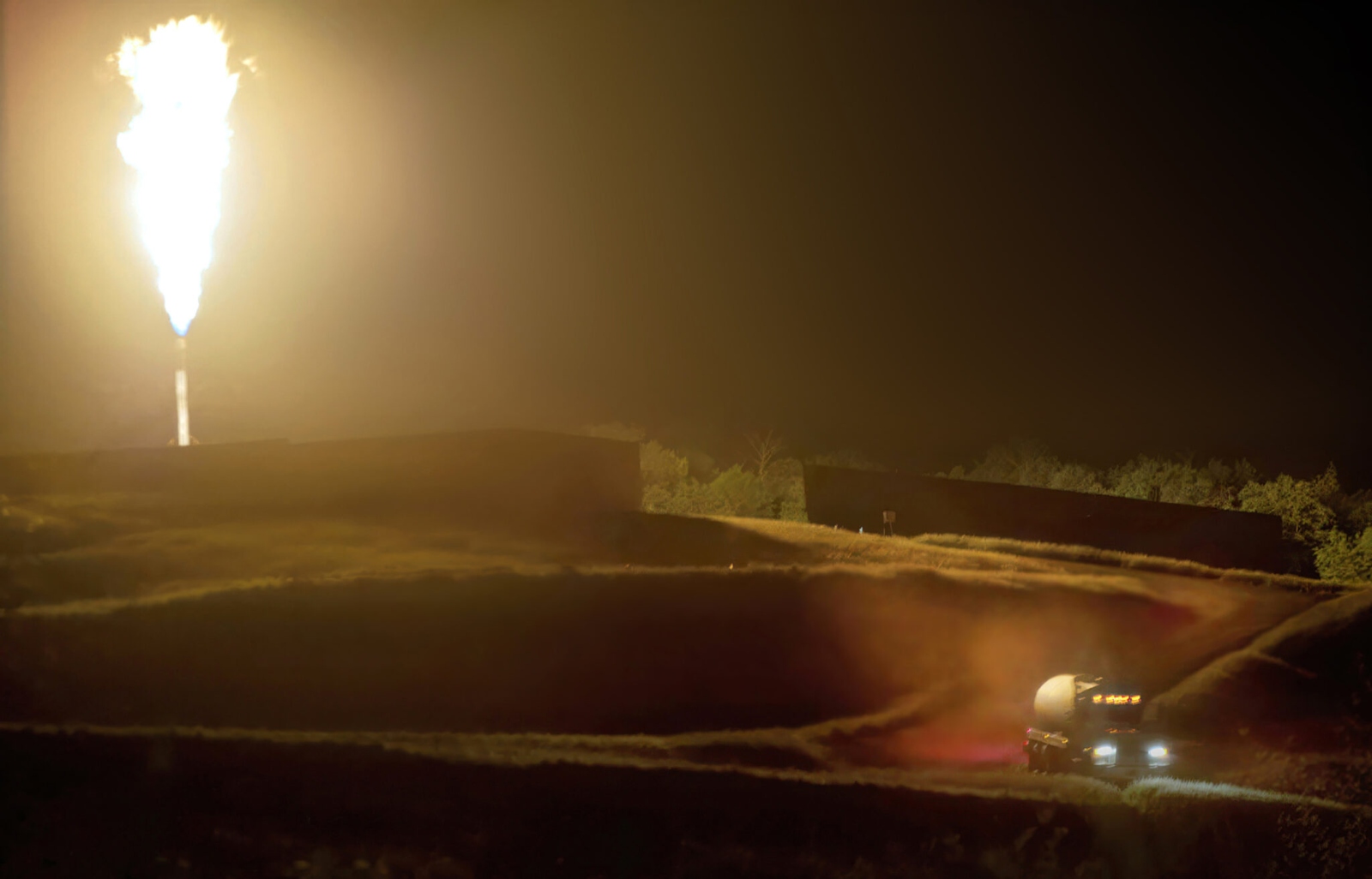 A nighttime scene of a truck and a column of fire.
