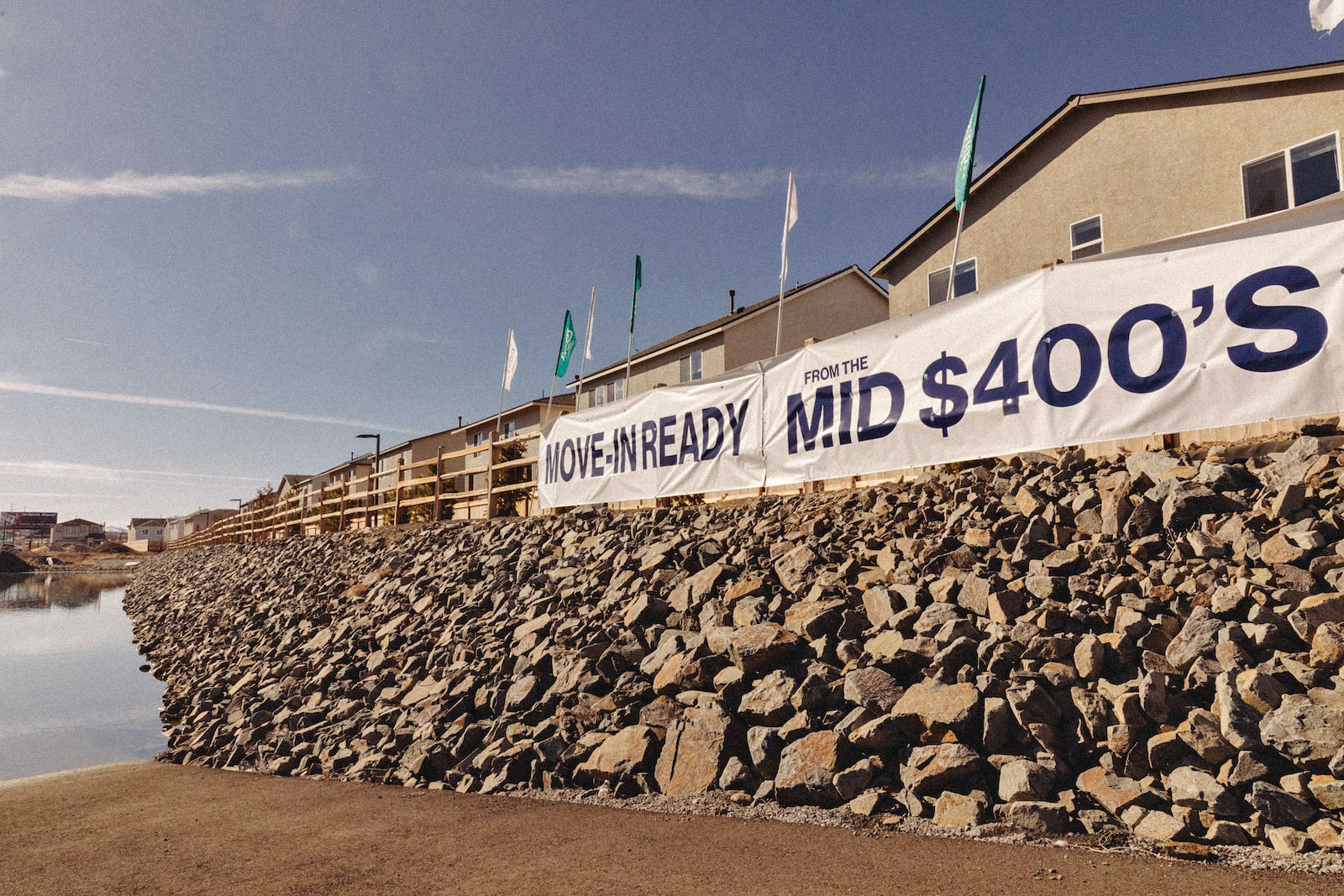 a large rock wall with houses has a sign that reads "move-in ready mid-$400s"