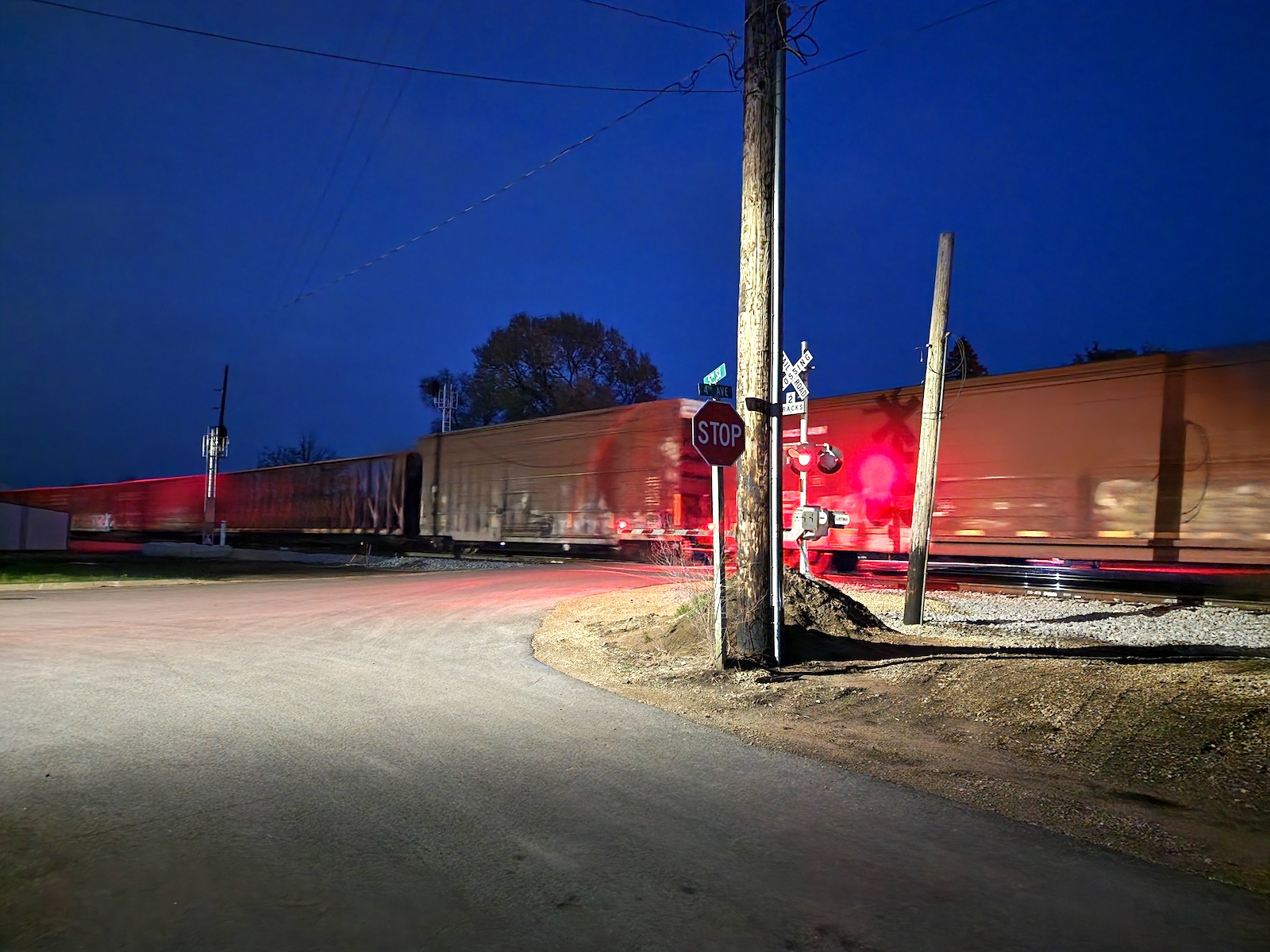 a blurry train goes through a railroad crossing at night