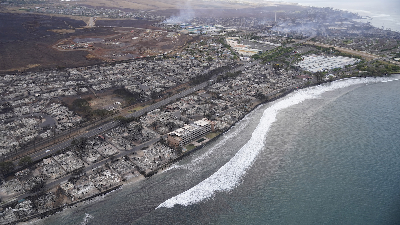 an aerial photo of the coast and burned out shells of buildings