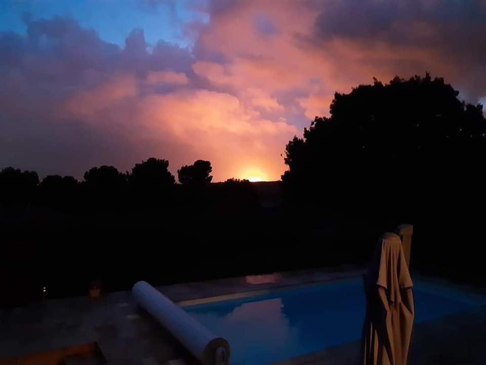 The sky glows with fire over a pool.