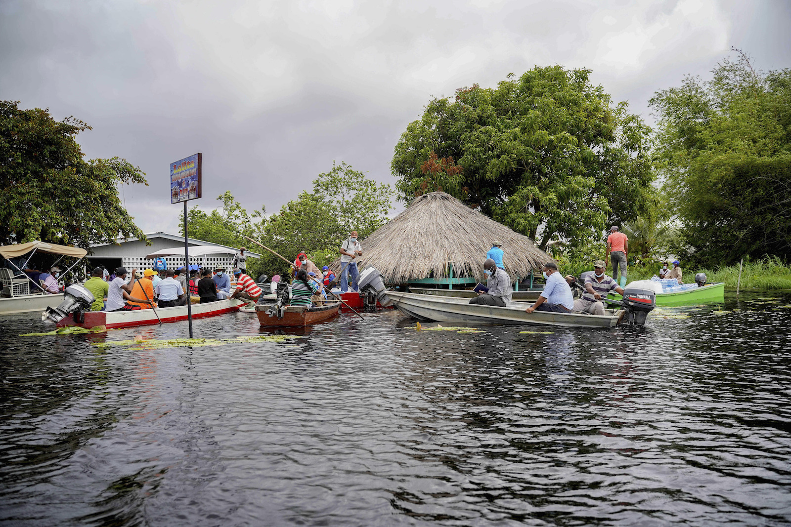 boats float on flood waters near a thatched hut