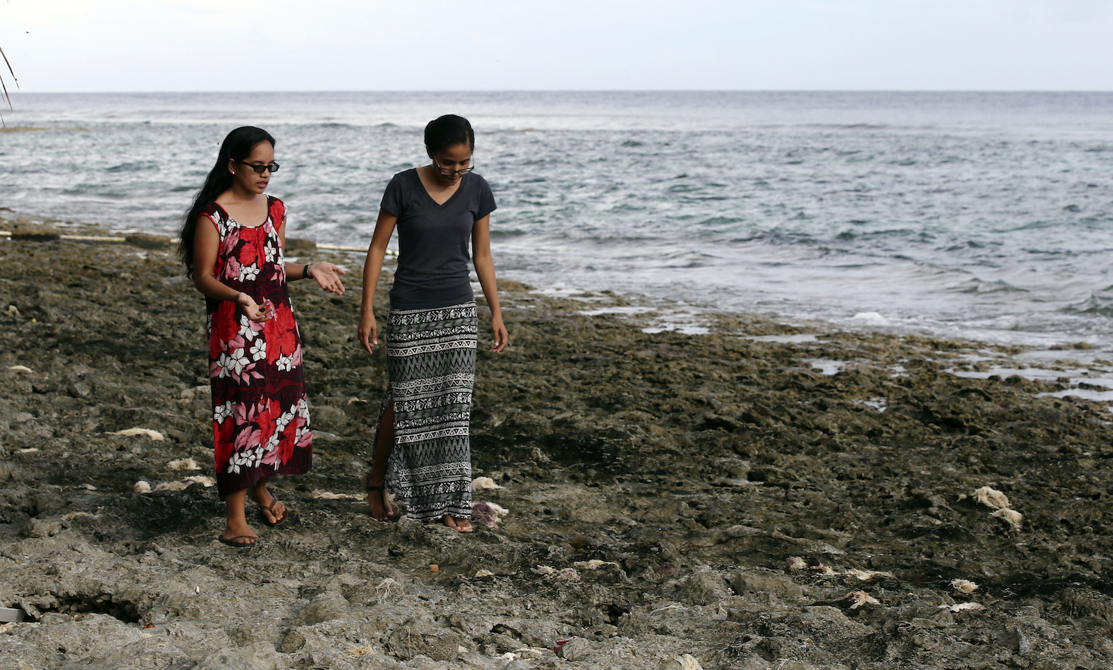 Two women walk along a rocky sea shore