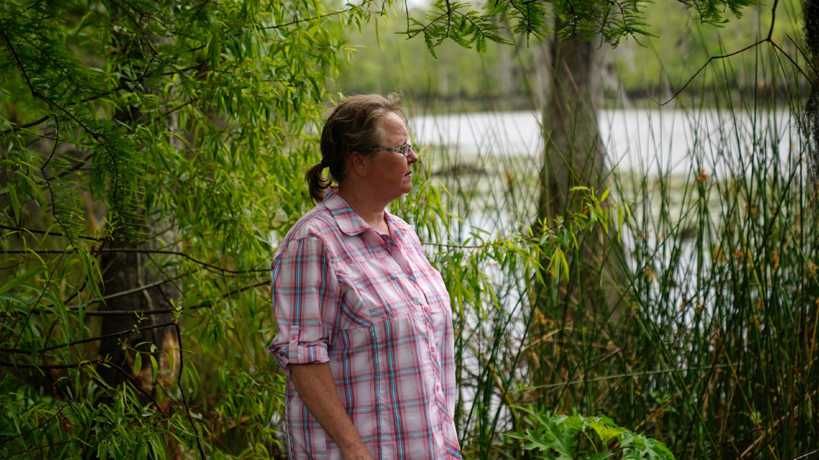 A concerned resident stands next to a river near Lake Maurepas in Louisiana, where she worries about the environmental impacts of new carbon capture projects.